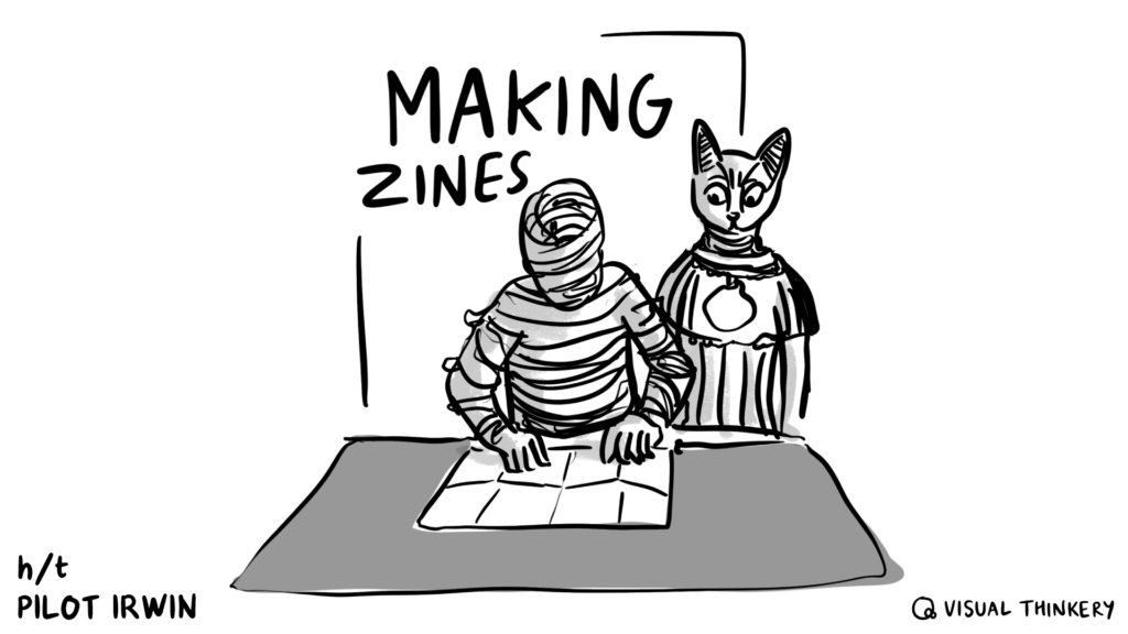 An Ancient Egyptian cat watches a mummy fold a zine.